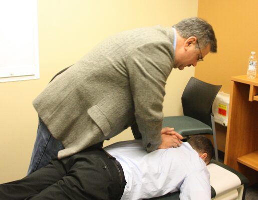 Chiropractor performing a spinal adjustment on a patient lying on a treatment table